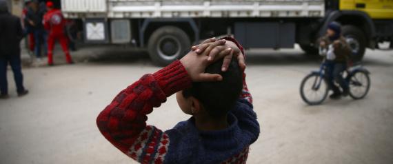 A boy gestures near a Syrian Arab Red Crescent truck in the besieged town of Douma, eastern Ghouta, in Damascus